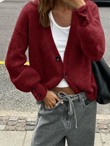 Détail d'un cardigan rouge en maille avec col en V et boutons noirs élégants sur les poignets