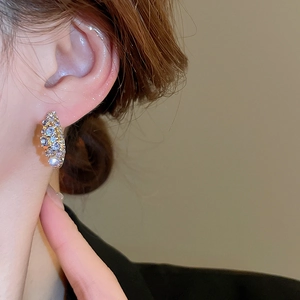 Macro side view of crystal-encrusted gold hoop earrings with lilac rhinestones on ear