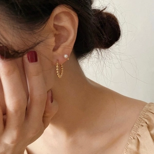 Close-up of elegant gold hoop earrings with white freshwater pearls worn by a model