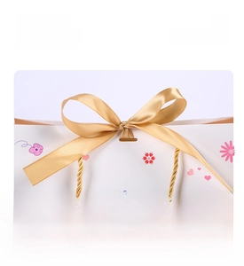 Close-up of a gift bag featuring a golden ribbon closure and cute cartoon patterns