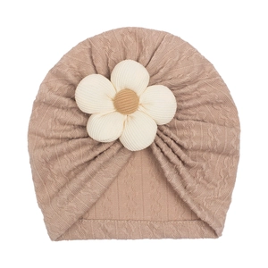 Khaki baby turban hat with a large white flower knit decoration on a soft ribbed fabric