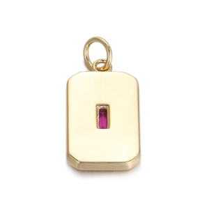 Close-up of a rectangular gold pendant with a small red gemstone on white background