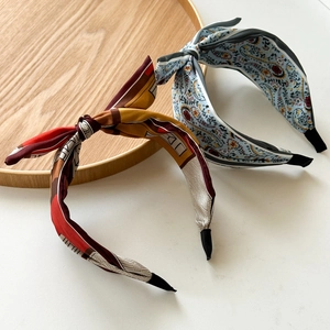 Detail of twisted satin headbands with geometric and paisley patterns on marble background