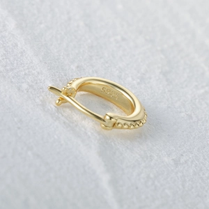 Macro shot of S925 sterling silver gold earring with hallmark on stone background
