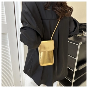 Chic gold metallic crossbody phone bag with elegant shoulder strap on black shirt
