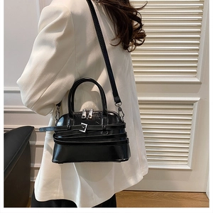Detail of black glossy shell bag with silver buckle straps and adjustable shoulder strap