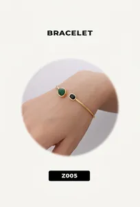 Detail of an asymmetric open cuff bracelet with green and black oval gemstones