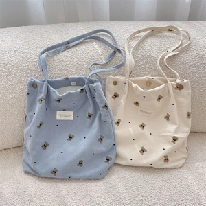 Détail de sacs cabas en velours côtelé bleu et beige avec ours imprimés et fermoirs en métal