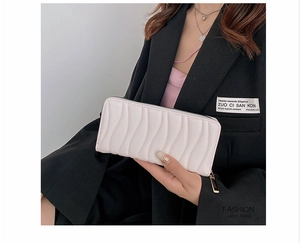 Detailed close-up of a long cream-white PU leather wallet with wavy vertical texture