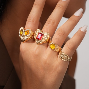 Detailed view of four vintage gold resin rings with heart and geometric patterns on a hand