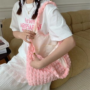Close-up of pink puff textured tote bag with interior pocket on a cozy sofa setting