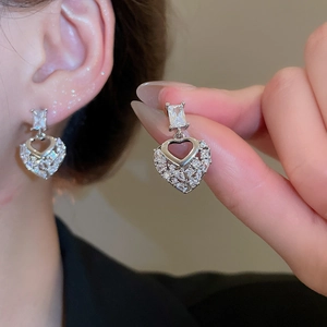 Detail view of heart-shaped silver earrings with sparkling white cubic zirconia stones