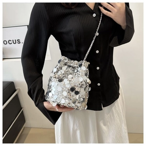 Detailed close-up of shiny silver sequin bucket bag with elegant woven metal chain strap