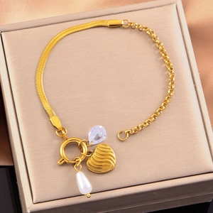 Detail of gold snake chain bracelet with heart, pearl and gemstone charms in a jewelry box