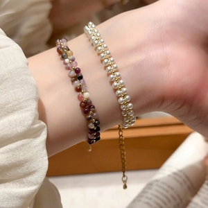 Detail of beaded bracelet with colorful natural stones, white pearls and gold extension chain