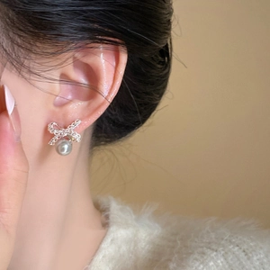 Detailed view of silver bow earrings with round white pearls on a female model