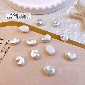 Detailed macro view of 10x8mm irregular baroque pearl nail art charms on a pink surface