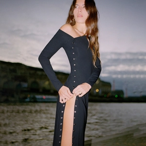 Elegant one-shoulder black long sleeve dress with buttoned side slit and slim fit silhouette