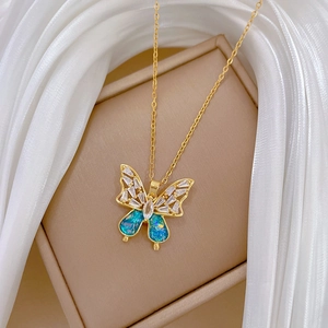 Macro detail of blue butterfly pendant with clear crystals and gold chain on silk