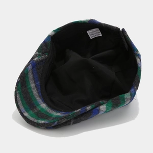 Detail view of colorful plaid flat cap showing wool blend fabric and inner lining