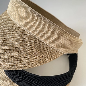 Detailed top view of beige straw visor hats with fine weave and gold metal emblem