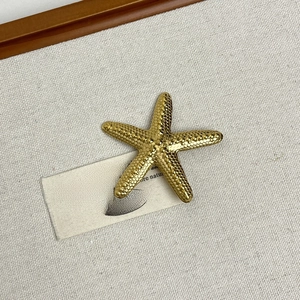 Detail of a golden starfish brooch with textured surface on soft fabric background