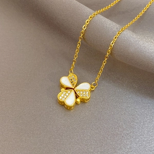 Gros plan du collier trèfle doré avec incrustations de nacre et zircons blancs