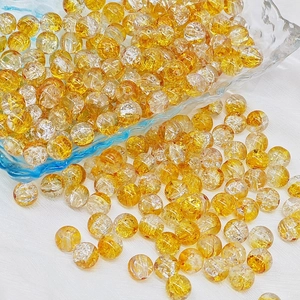 Macro view of 6mm yellow crackle glass beads scattered in a blue bowl for DIY jewelry