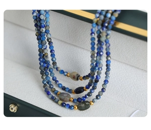 Detail of a handmade multi-layer natural stone beaded necklace with gold metal accents