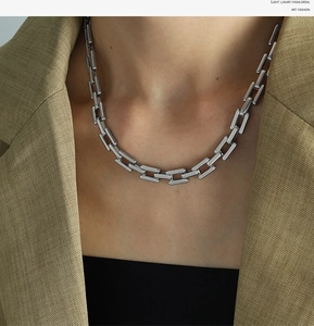 Close-up of a silver chunky rectangular link chain necklace worn on a fashion model