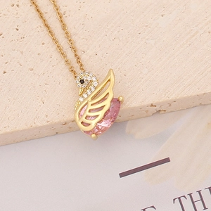 Detailed close-up of golden swan pendant with pink heart gemstone and mini diamonds