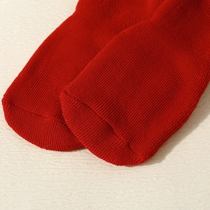 Close-up of red knit baby socks showing detailed stitching and thick ribbed texture