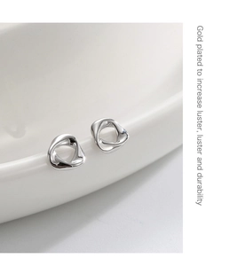 Detailed view of silver minimalist twisted geometric studs on white ceramic dish