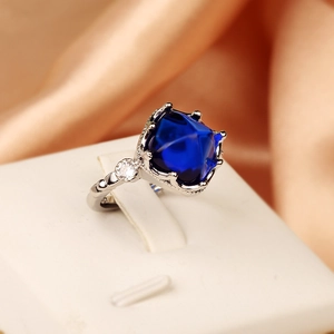 Luxury open ring featuring square blue sapphire stone and side diamonds on silk background