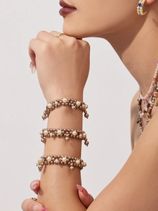Detail view of retro Hepburn style cream pearl and brown beaded bracelets on wrist