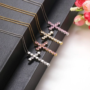 Macro detail of cross pendant necklaces with pink and white cubic zirconia on black box