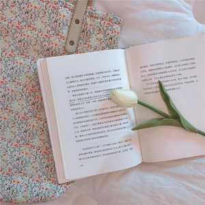 Close-up of floral cotton pouch with metal rivet hardware on light textured bedding