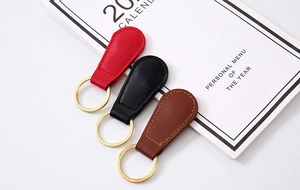 Detailed view of red, black, and brown PU leather magnetic keychains with gold metal rings