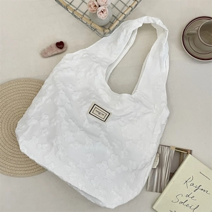 Detail of white jacquard tote bag with 3D floral texture and Pleasant Time label
