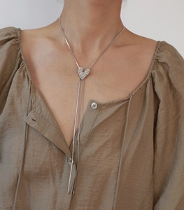 Close-up of heart pendant and silver long chain necklace on a model for autumn outfit
