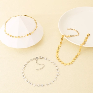 Trois bracelets en acier inoxydable doré et argenté avec breloques disques sur support beige