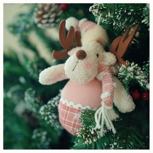Detailed view of pink and white plush reindeer ornament hanging on a Christmas tree branch