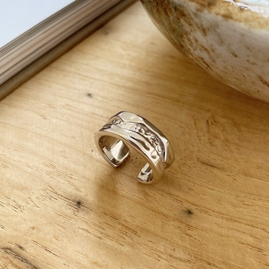 Detail of S925 sterling silver ring with irregular lava texture on wooden background