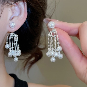 Detail of silver drop earrings with white pearls and sparkling tassel chandelier style