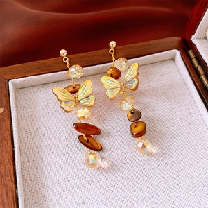 Close-up of golden crane butterfly earrings with resin beads in a vintage wooden box
