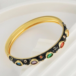 Golden enamel bangle with colorful zircon stones in a retro bohemian design on white pedestal