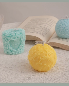 Detail of colorful scented candles with floral relief patterns on white knit fabric