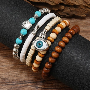 Detail of layered turquoise and wood bead bracelets with evil eye and paw charms
