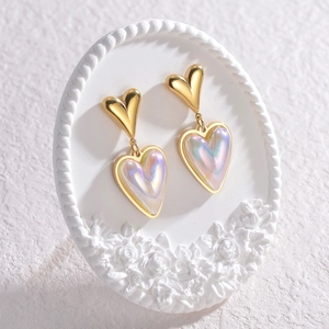 Elegant gold heart earrings with iridescent inlays on a white floral display plate