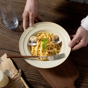Handcrafted Japanese style ceramic pasta plate with clams on a rustic wooden table